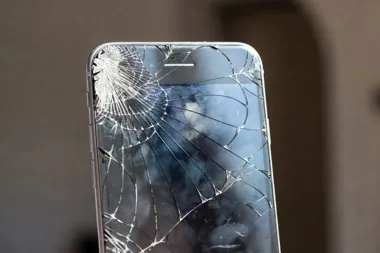 Smartfon z mocno pękniętym ekranem, z rozbitym szkłem w lewym górnym rogu.