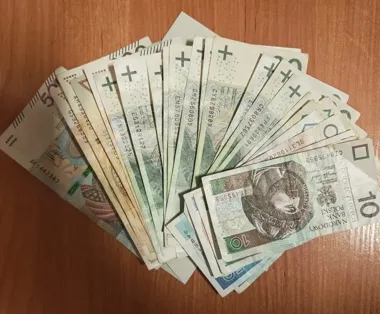 Rozłożone na drewnianym blacie banknoty polskie różnych nominałów.