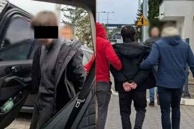 Funkcjonariusze prowadzą zatrzymanego w kajdankach mężczyznę do samochodu na ulicy miasta.
